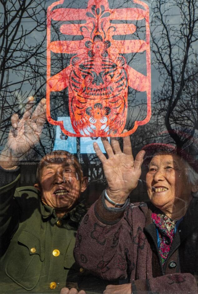 臘月里，霍州市師莊鄉(xiāng)馮南垣村村民師榮光(左)在災(zāi)后重建的新家里貼窗花。(霍州市委宣傳部供圖)