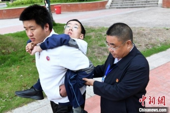 朱金祥背著鐘華強(qiáng)去教室上課的路上，也經(jīng)常碰到值班的校領(lǐng)導(dǎo)和老師前來搭把手。 卓忠偉 攝