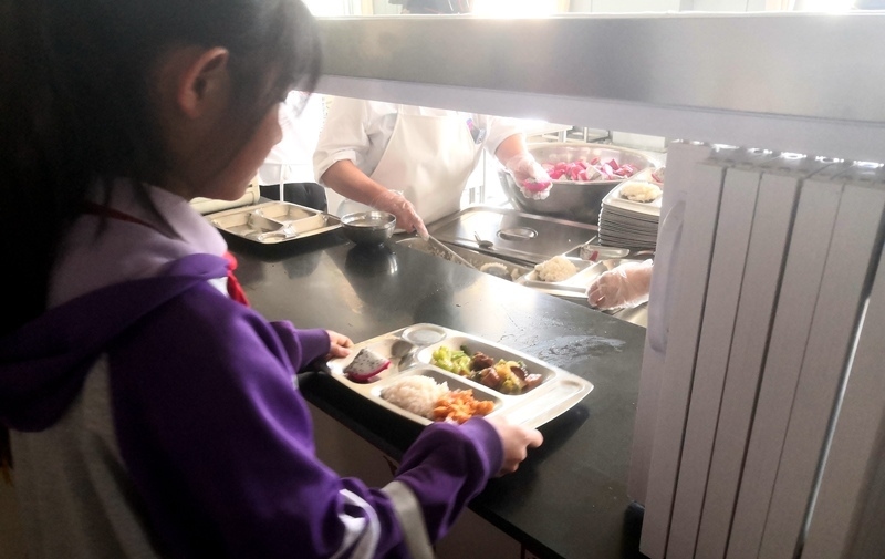 伊金霍洛旗第一小學(xué)學(xué)生正在打飯，今天的飯菜是三菜一湯外加水果，學(xué)生可以多次盛取，吃飽為止。人民網(wǎng)記者 孫博洋攝