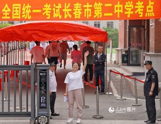 6月7日，在長春市第二中學(xué)考點，一名考生信心滿滿進入考場，并與家長揮手致意。人民網(wǎng)記者 李洋攝