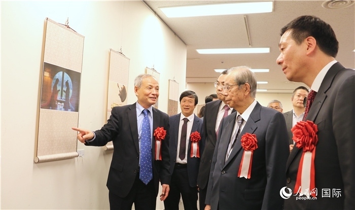 “湖州印象”攝影展主創(chuàng)、世界華人攝影協(xié)會副會長馮學敏向吳江浩大使、福田康夫前首相等嘉賓介紹展出作品。（人民網(wǎng) 許可攝）