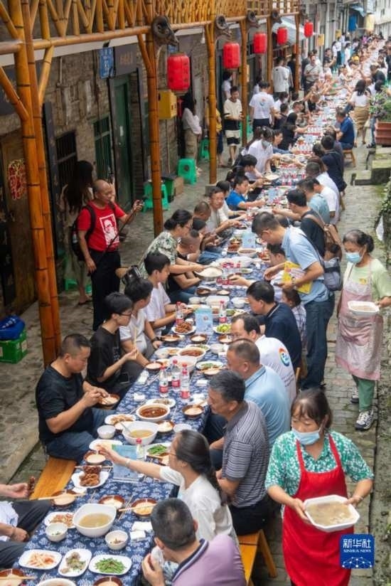 7月29日，在重慶市綦江區(qū)安穩(wěn)鎮(zhèn)，人們在“苗家伏羊節(jié)”上吃長桌宴。新華社記者 唐奕 攝