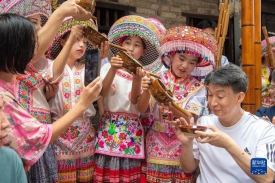 7月29日，在重慶市綦江區(qū)安穩(wěn)鎮(zhèn)，當?shù)鼐用裨凇懊缂曳蚬?jié)”上用傳統(tǒng)習俗向游客表達祝福。新華社記者 唐奕 攝