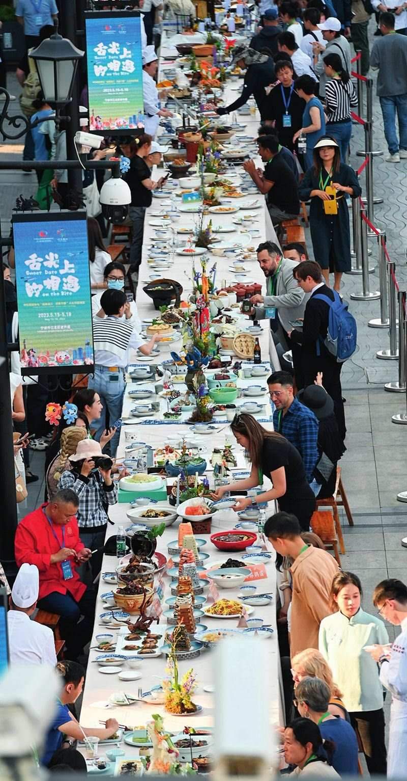 市民和游客在寧波舉辦的第三屆中國(guó)—中東歐國(guó)家博覽會(huì)暨國(guó)際消費(fèi)品博覽會(huì)上品嘗融合中國(guó)和中東歐美食的長(zhǎng)桌宴（2023年5月15日攝）。黃宗治攝/本刊