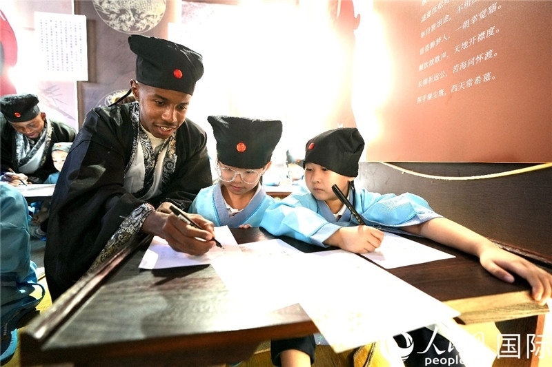 圖為選手與同學(xué)們一起寫(xiě)書(shū)法。人民網(wǎng) 盧鵬宇攝