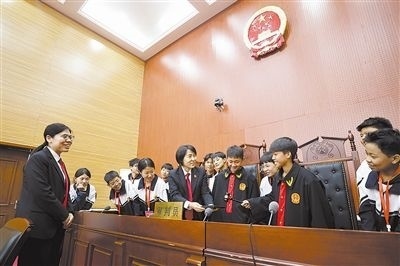 圖③：同學(xué)們穿法袍、敲法槌，爭做“小法官”。