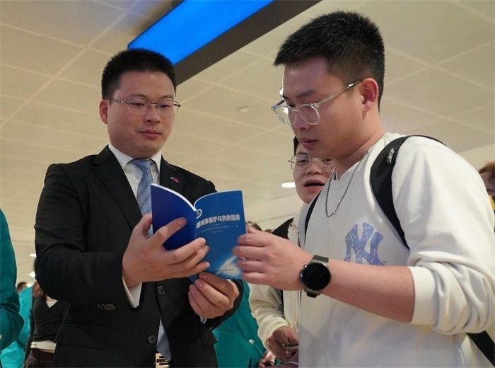 工作人員（左一）在發(fā)放《中國領(lǐng)事保護(hù)與協(xié)助指南》。 中國駐迪拜總領(lǐng)事館供圖