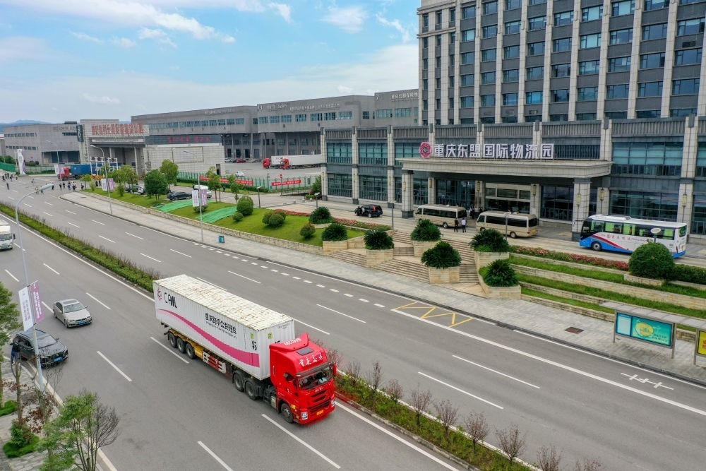 2023年10月11日，滿載筆記本電腦配件、發(fā)電機組件等產(chǎn)品的西部陸海新通道跨境公路班車從重慶南彭公路保稅物流中心駛出，將途經(jīng)廣西憑祥，直達越南（無人機照片）。新華社記者 黃偉 攝