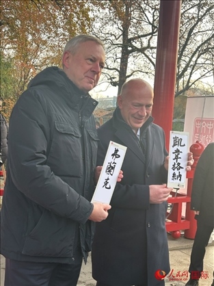 柏林市長韋格納（右）、動物園監(jiān)事會主席布魯克曼（左）手持中國文化中心工作人員現場手書的中文名字。人民網記者 徐馨攝