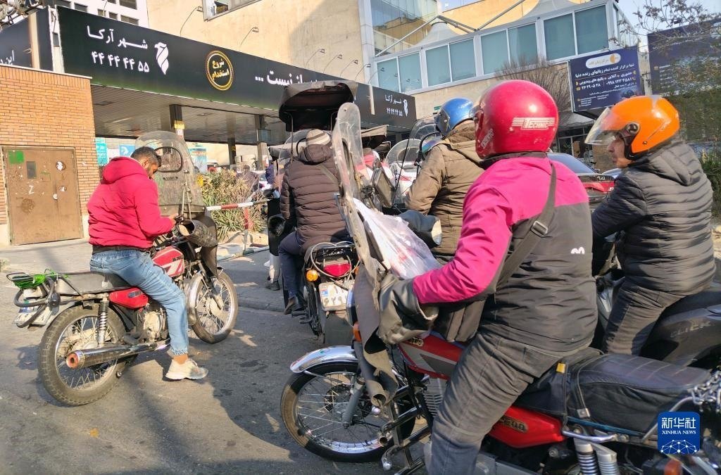 12月18日，摩托車在伊朗首都德黑蘭的一家加油站外等待加油。新華社記者 沙達提 攝