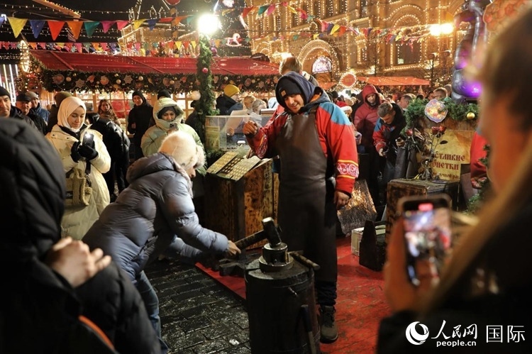 游客在新年集市上體驗(yàn)制作紀(jì)念幣。人民網(wǎng)記者 隋鑫攝