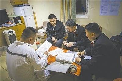圖②：法官向船長(zhǎng)講解相關(guān)法律規(guī)定，查看船舶資料，并與船方辦理扣押船舶的手續(xù)。