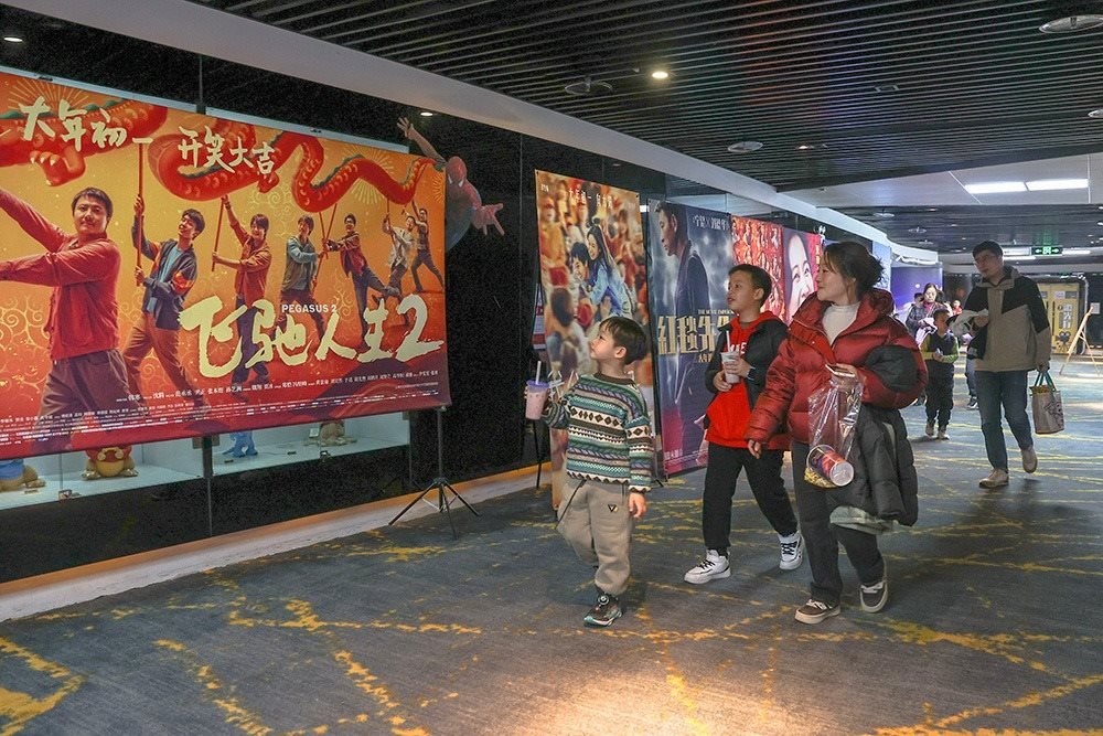 △ 2024年2月16日，在江西贛州一家電影院，觀眾從春節(jié)檔電影的宣傳展板前走過。