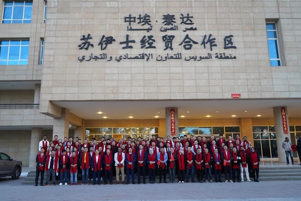2024年2月11日，在位于埃及蘇伊士省的中?！ぬ┻_(dá)蘇伊士經(jīng)貿(mào)合作區(qū)，中埃員工在合作區(qū)辦公大樓前合影拜年。新華社發(fā)（泰達(dá)合作區(qū)供圖）