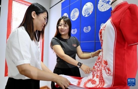 5月31日，在衡水市阜城縣一家剪紙工作室，游客在觀賞帶有剪紙元素的旗袍。