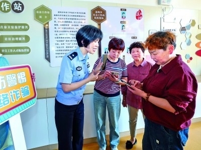浙江湖州民警指導(dǎo)居民加入湖州“e企安”微信群，實時接收反詐信息。新華社發(fā)