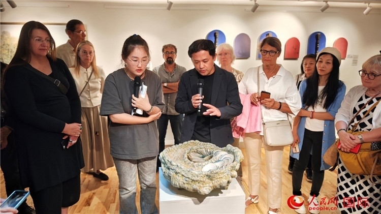 參展人、景德鎮(zhèn)陶瓷大學(xué)設(shè)計藝術(shù)學(xué)院副院長余劍峰（中）向來賓介紹參展作品。人民網(wǎng)記者 殷淼攝