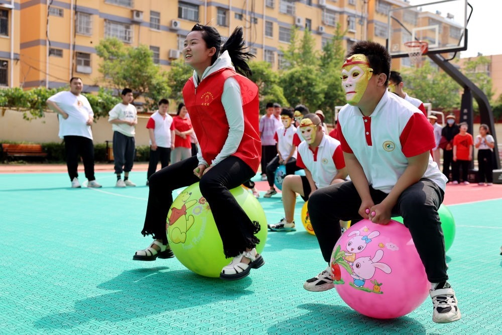 2024年5月17日，在山東省棗莊市市中區(qū)特殊教育中心，青年志愿者與智力障礙學(xué)生一起做游戲。新華社發(fā)（孫中喆攝）