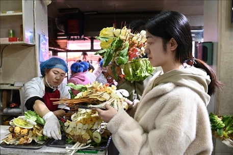 游客挑選好麻辣燙菜品后排隊等待加工。新華社記者 范培珅 攝