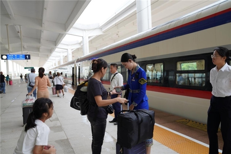 中老鐵路工作人員在站臺指引旅客進(jìn)站乘車。老中鐵路有限公司供圖