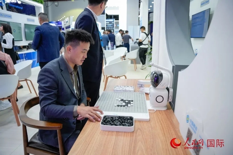 觀眾在中國移動國際有限公司展臺體驗智慧圍棋機器人。人民網(wǎng) 塔里克·易卜拉欣攝