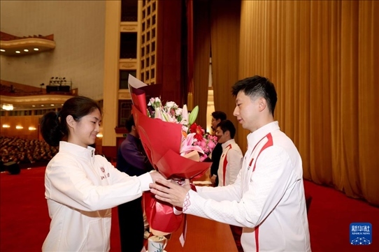 11月15日，一名學(xué)生代表在報(bào)告會(huì)上向乒乓球運(yùn)動(dòng)員馬龍（右）獻(xiàn)花。新華社記者 李明 攝