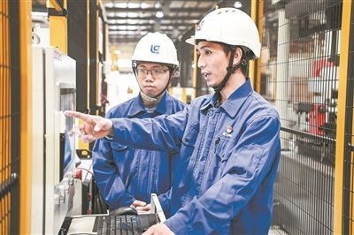 在廣西柳工機(jī)械股份有限公司生產(chǎn)車間內(nèi)，一名高級(jí)技師（右）給徒弟講解數(shù)控設(shè)備操作細(xì)節(jié)。新華社記者 曹祎銘攝