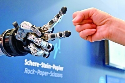 在德國漢諾威工博會上，參觀者與一款智能機器人進(jìn)行“石頭剪子布”游戲。新華社發(fā)