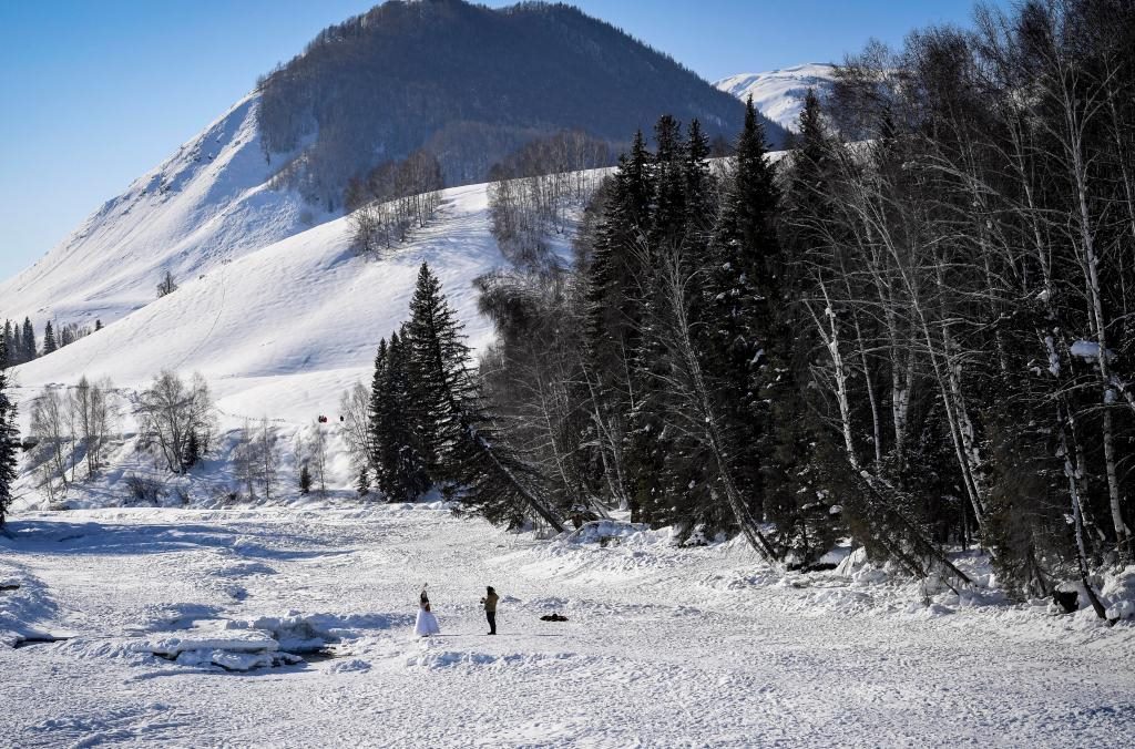 2024年2月5日，兩名游客在新疆阿勒泰地區(qū)布爾津縣禾木村拍照。新華社記者 馬鍇 攝