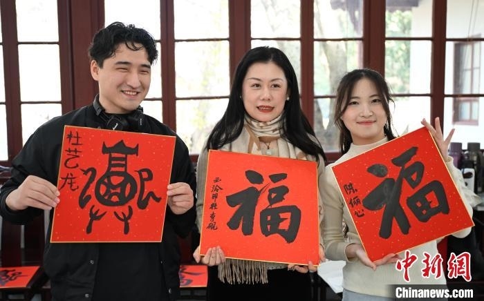 1月20日，外籍留學(xué)生和西泠印社社員李硯(中)展示各自創(chuàng)作的福貼。當(dāng)日，來自巴西、馬來西亞、加納、哈薩克斯坦的外籍留學(xué)生在浙江杭州西泠印社體驗福貼、春聯(lián)和篆刻，感受古老的中國傳統(tǒng)文化。中新社記者 王剛 攝