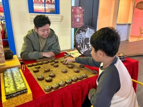 柯秋楓與市民下椰雕象棋。人民網(wǎng) 陳葉欣攝