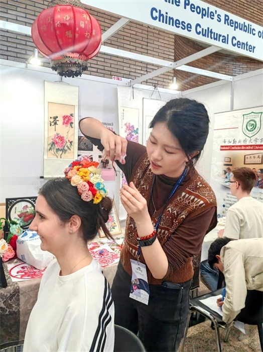 展覽正值羅馬尼亞迎春花節(jié)，國際中文教師志愿者潘婧穎向游客們介紹了國家非物質(zhì)文化遺產(chǎn)——福建泉州的簪花文化。布加勒斯特大學(xué)孔子學(xué)院供圖。